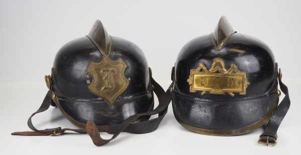 4.1.) Uniformen / Kopfbedeckungen Zwei Feuerwehr-Helme.Je Lederhelm mit Messingemblem.Zustand: II