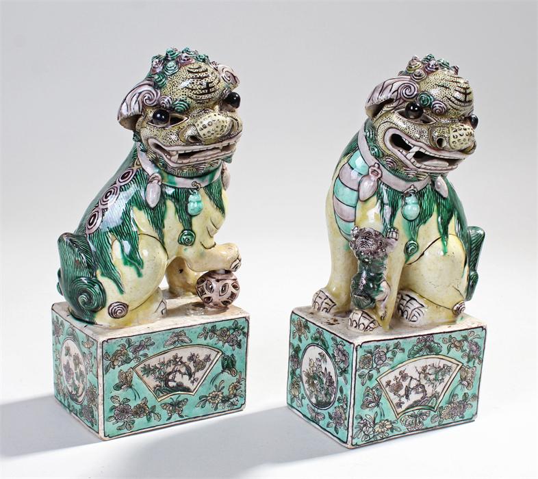 Pair of Chinese dogs of Fo, decorated in greens, yellows and violet, one standing on a ball the - Image 2 of 2