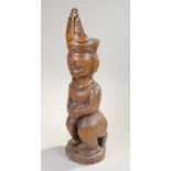 Ethnographical figure. the large figure in a seated position with a large head dress, 67cm high