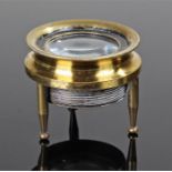 19th Century brass simple microscope, the lens raised upon three turned supports, 4.5cm wide