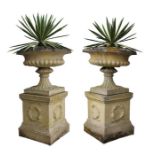 Pair of composite garden urns, with a squat body a gadrooned base above a vase column and wreath