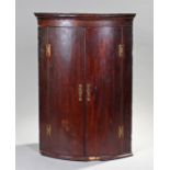 George III mahogany bow front corner cabinet, the concave cornice above a pair of doors opening to