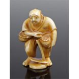 Meiji period Japanese ivory netsuke, carved as a standing figure holding a basket and a tool to