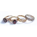 9 carat gold rings, to include a garnet flower head example, a lattice example, a stone set