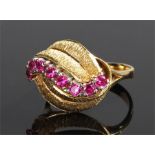 18 carat gold ruby ring, with an arched band of rubies between two pairs of leaf design bands,