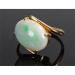 Yellow metal jade set ring, with an oval jade stone set to the scroll head