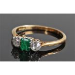 18 carat gold emerald and diamond ring, the central emerald flanked by a diamond to each side,