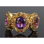 Victorian yellow metal and amethyst bangle, set with three facetted amethyst and foliate scroll