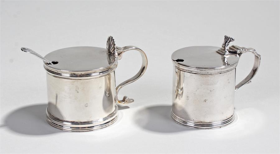 Two silver mustards, the first Birmingham 1928, with a hinged lid and shell cap above the drum body,