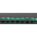 Chinese jade bracelet, with a row of ten oval carved jade plaques on white metal, 17cm long