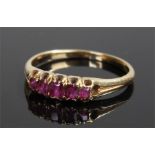 Yellow metal ruby set ring, with a row of five rubies to the head, ring size M