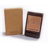 Jaeger desk timepiece, the orange/gilt dial with luminous hours and signed dial, leather folding