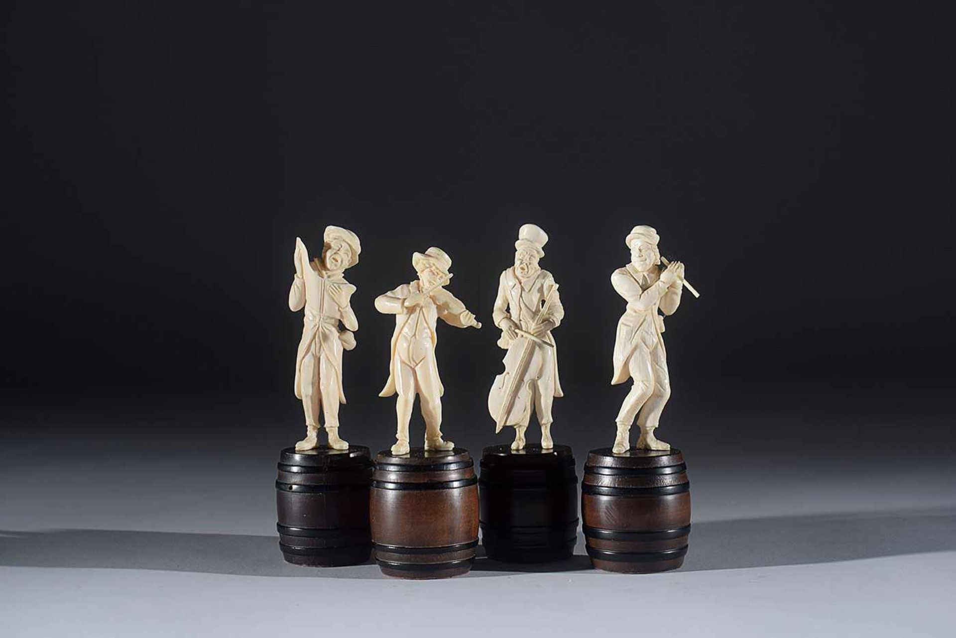 Four Dutch ivory sculptures of a musician standing on a barrel 19th century, total height 15cm.