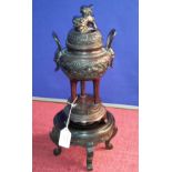 Oriental bronze censor pot on 3 pedestal legs situated on bronze base which sits on hard wood stand,