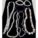 A collection of freshwater pearls, some with pastel shading and one purple glass bracelet