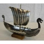 A white metal Viking ship on wooden stand. 15 x 21cm