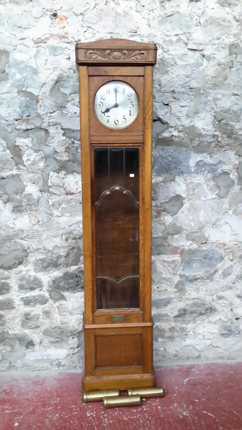 A 1920's oak long cased grandfather clock with bevel glass front with weights & pendulum
