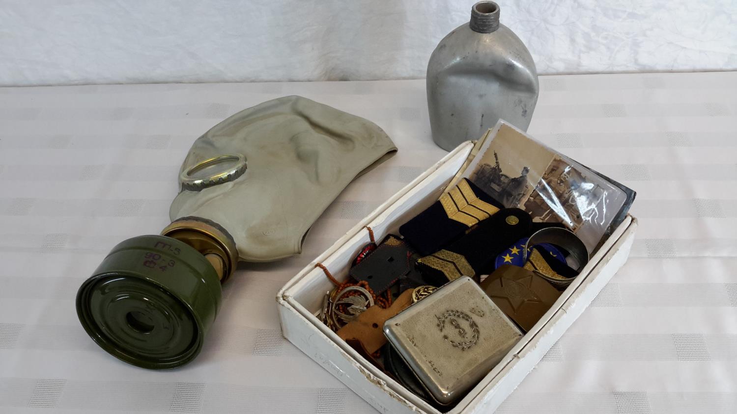 A collection of military badges, patches, gas mask & bottle