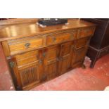 A reproduction oak sideboard with three frieze drawers and linen carved cupboards 103cm high,
