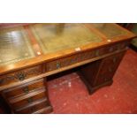 A reproduction oak pedestal desk the tooled writing surface above nine drawers 80cm high, 128cm wide