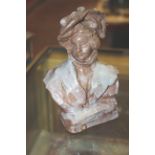 An early 20th century fired clay bust of a young woman wearing a hat, indistinctly signed to the