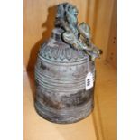 A Chinese bronze bell moulded with dragon faces, 35cm high,