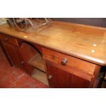 A pitch pine side cabinet with arched central section flanked by drawers and cupboards 92cm high,