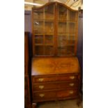 An early 20th Century walnut bureau bookcase with arched and glazed upper section, with three