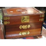 A Chinese hardwood jewellery box with ornate brass banding and red silk lining to the top and two