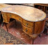 An early 20th Century walnut kidney shaped table with tooled writing surface, five drawers and shell