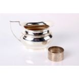 Silver; A silver milk jug, Chester 1918, 4.1 troy oz or 130g and a silver napkin ring (2)