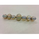 A gold and opal bar brooch, the central oval opal 12mm x 10mm, flanked by three graduating opals