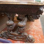 A Victorian carved oak library table with lion masks at each corner and standing on dolphin mask