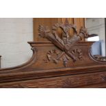 A French carved headboard with crossed torches to the cresting panelled back flanked by columns
