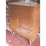 An Ercol style elm desk with drop front and drawers and cupboard below on splayed legs