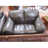 A pair of modern black leather sofas and a footstool