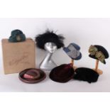 An early 20th Century velvet and feather hat within a Woolland Bros hat box; a 1940s burgundy hat, a