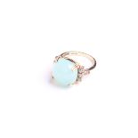 An opaque pale-blue cabochon dress ring, possibly Beryl, between pale-blue three stone and small