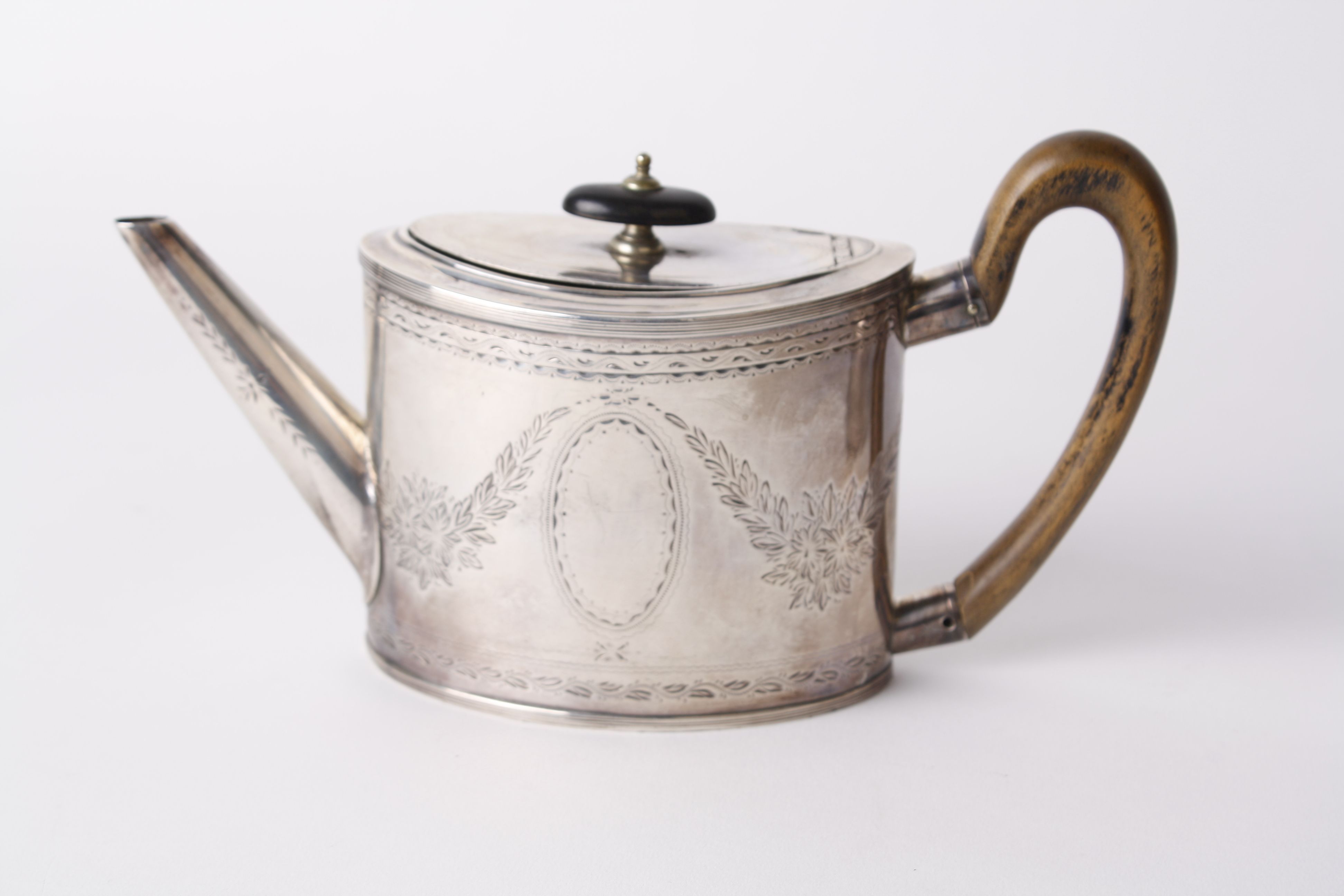 A 19th century Duth oval small teapot, the straight sides engraved with leaves and oval cartouche,