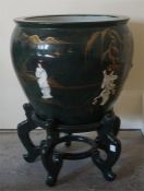 Large Green and Guilt Jardinere with raised figure decoration standing on a green lacquered base.