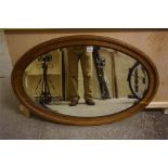 A late 19th Century oak oval wall mirror with bevelled glass- 14" wide