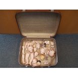 A vintage suitcase containing a quantity of modern heads and various doll's body parts