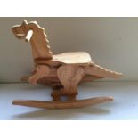 A carved wooden ride on rocking toy in the form of a dragon. Unsold retail stock.