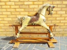 A wooden child's rocking horse on a wooden base approximately 80 cm (h)