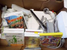 A Nintendo Wii game console with balance board, sound bar accessories, Nunchuk, WiiFit book,
