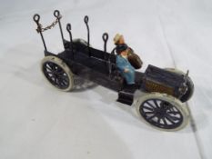 A early 20th century hand-painted metal model open lorry with two seated figures,