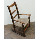 A child's antique elm rocking chair with rush seat