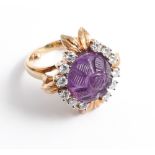 An unusual 18ct yellow gold set amethyst and diamond ring the central amethyst with carved floral