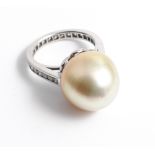 An unusual white gold large cultured pearl diamond dress ring with a full diamond channel set shank