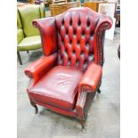 A Georgian style wing backed easy chair in red buttoned leather